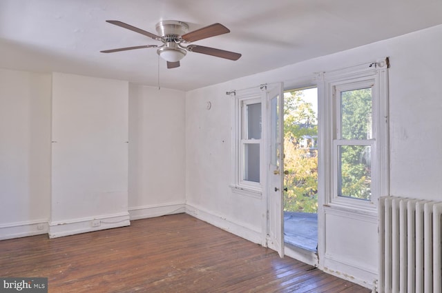 empty room featuring ceiling fan, radiator heating unit, and dark hardwood / wood-style floors