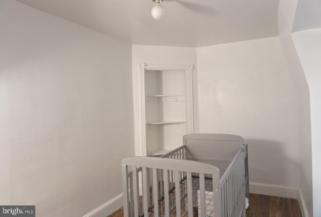 bedroom featuring a nursery area and dark hardwood / wood-style flooring