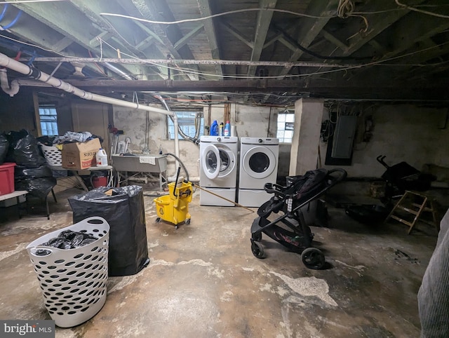 basement featuring independent washer and dryer, electric panel, and sink