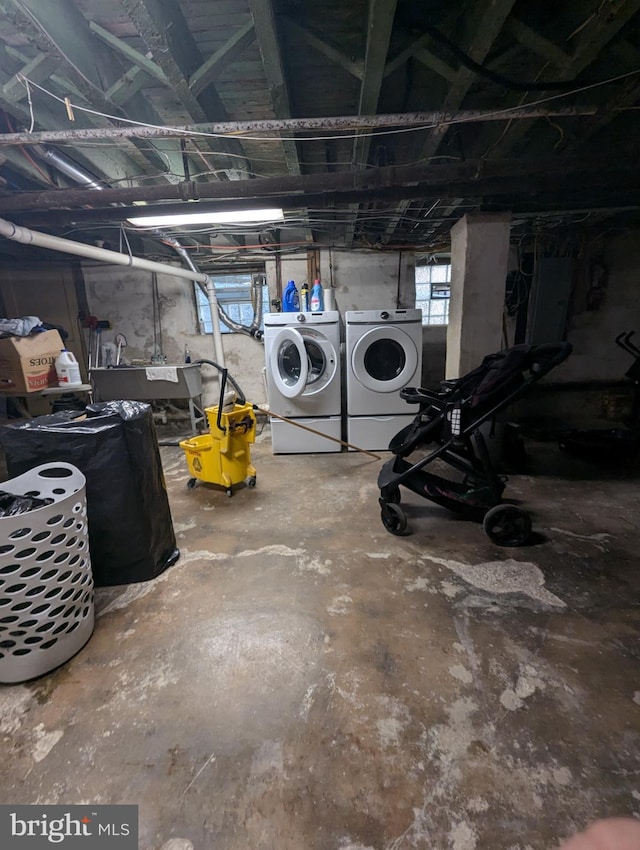 basement featuring separate washer and dryer, electric panel, and sink