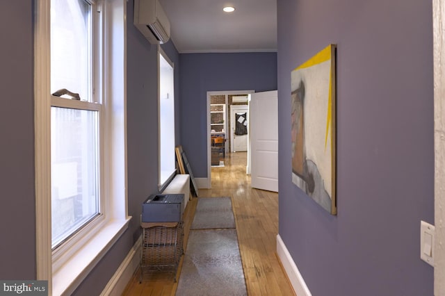 corridor featuring ornamental molding, light wood-type flooring, and a wall mounted AC