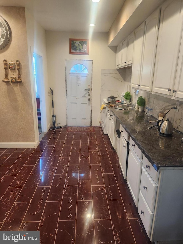 kitchen with dark stone countertops, white cabinets, and tasteful backsplash