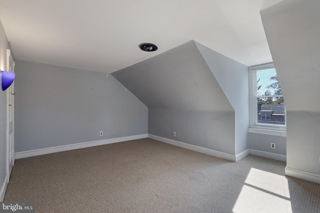 additional living space featuring lofted ceiling and light colored carpet