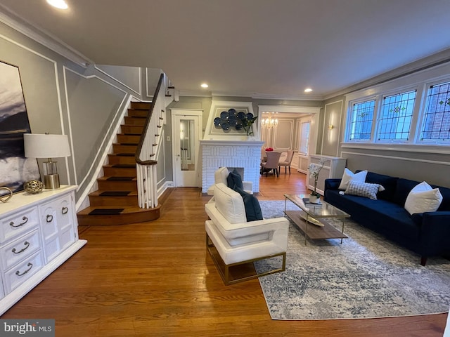 living room with crown molding, a fireplace, an inviting chandelier, and dark hardwood / wood-style floors