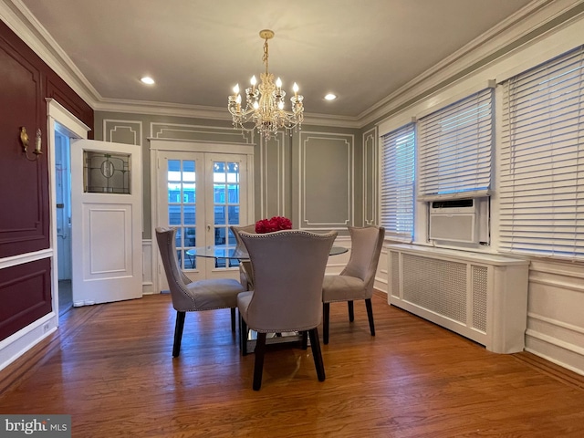 dining area featuring crown molding, hardwood / wood-style flooring, an inviting chandelier, and french doors