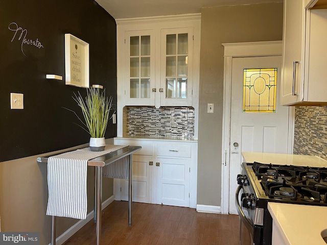 kitchen with dark wood-type flooring, gas range, tasteful backsplash, and white cabinets