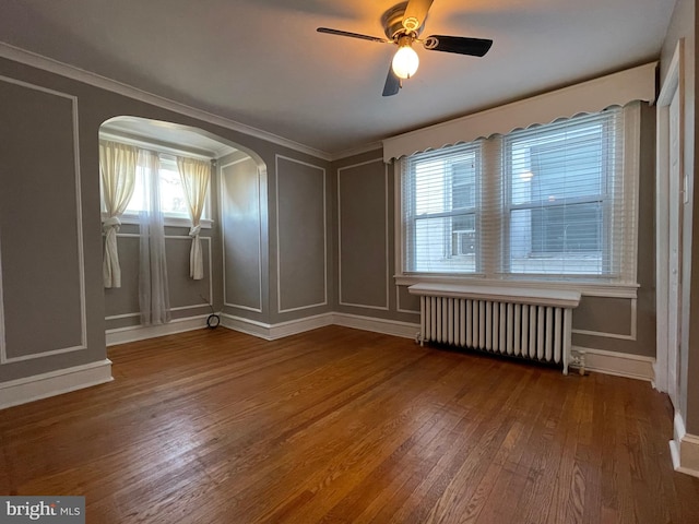 spare room with radiator, ceiling fan, a healthy amount of sunlight, and hardwood / wood-style floors