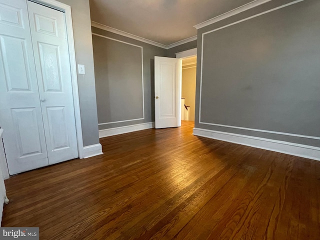 unfurnished bedroom with a closet, crown molding, and dark hardwood / wood-style floors