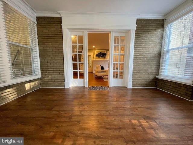 spare room with brick wall, ornamental molding, and dark hardwood / wood-style floors