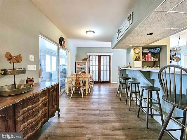 dining room with a drop ceiling, french doors, bar, and dark hardwood / wood-style floors