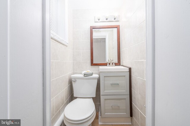 bathroom featuring vanity, tile walls, and toilet