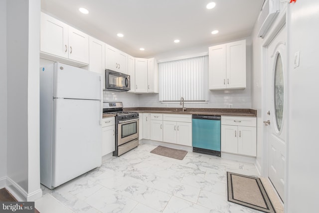 kitchen with tasteful backsplash, white cabinets, appliances with stainless steel finishes, and sink