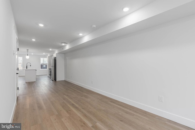 unfurnished living room featuring sink and light hardwood / wood-style flooring