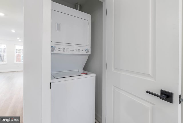 laundry room with stacked washer / dryer and light hardwood / wood-style flooring