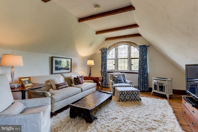 living room with wood-type flooring, vaulted ceiling with beams, and a wood stove