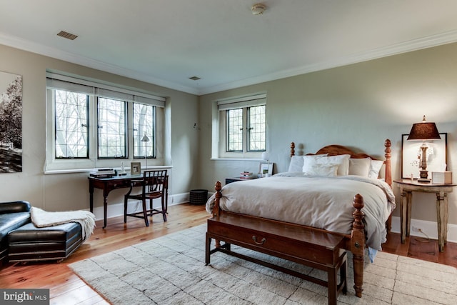 bedroom with light hardwood / wood-style flooring, crown molding, and multiple windows