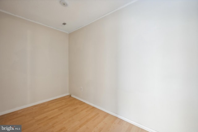 empty room featuring wood-type flooring and ornamental molding