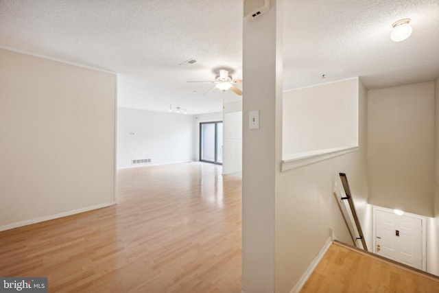 corridor featuring a textured ceiling and light hardwood / wood-style flooring