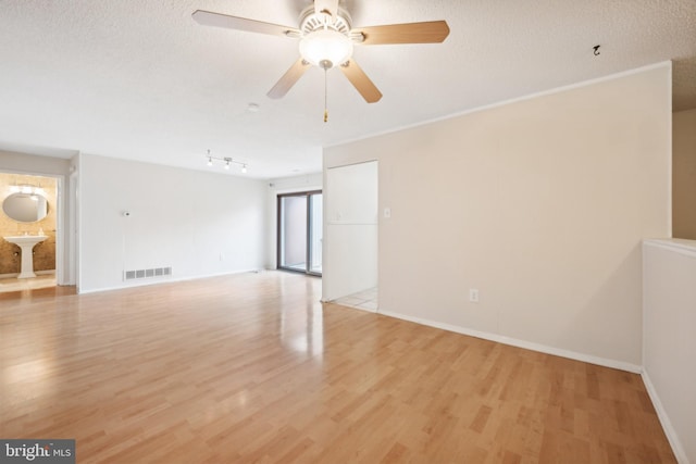 empty room featuring a textured ceiling, light hardwood / wood-style floors, ceiling fan, and rail lighting