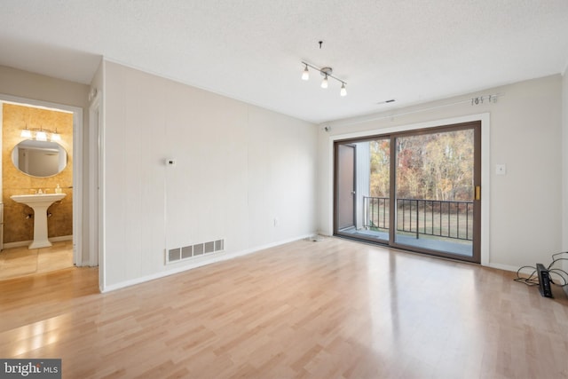 empty room featuring light hardwood / wood-style flooring, a textured ceiling, and sink