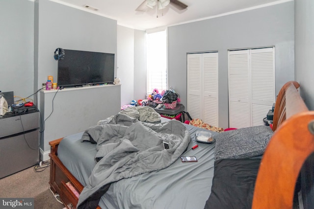 carpeted bedroom with multiple closets and ceiling fan