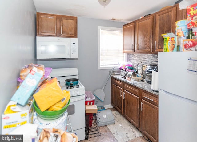 kitchen with decorative backsplash, sink, light stone counters, and white appliances