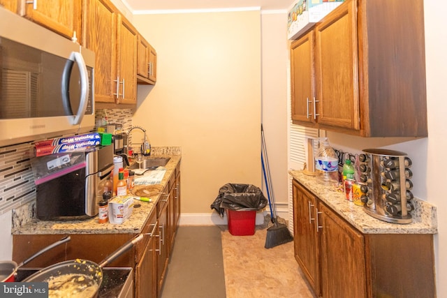 kitchen featuring light stone countertops, ornamental molding, sink, and backsplash