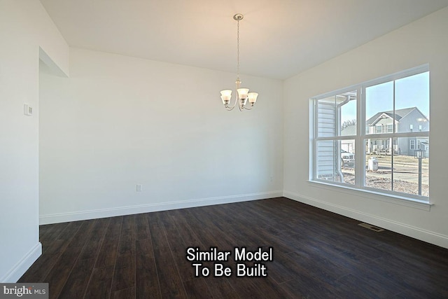 empty room featuring dark hardwood / wood-style flooring, a wealth of natural light, and a notable chandelier