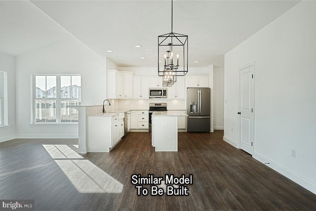 kitchen featuring stainless steel appliances, white cabinetry, a center island, lofted ceiling, and hanging light fixtures