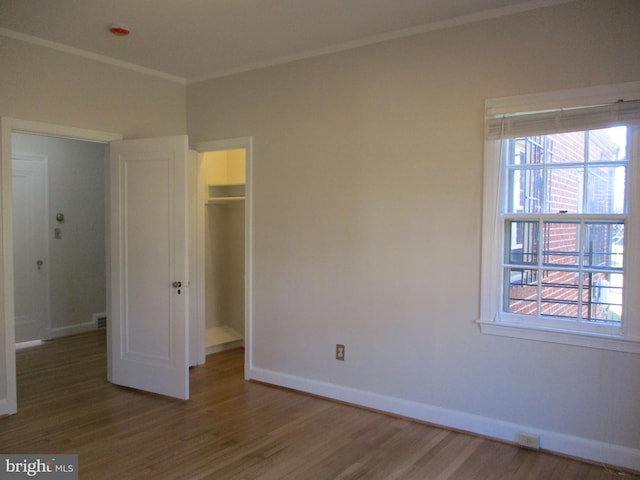 unfurnished bedroom with hardwood / wood-style flooring, a spacious closet, and a closet