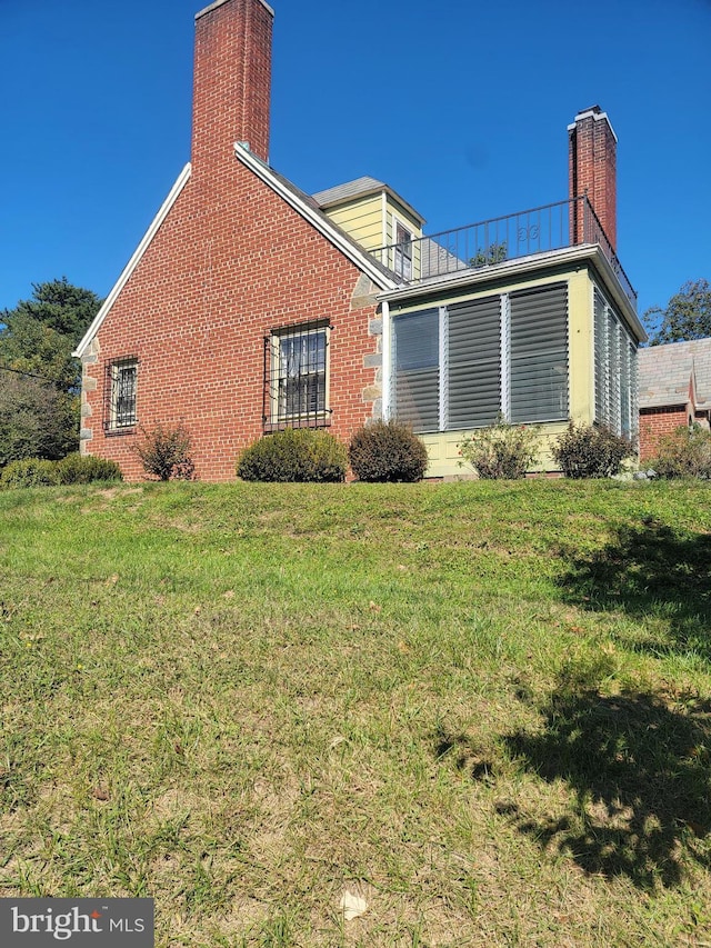 view of side of home featuring a balcony and a lawn