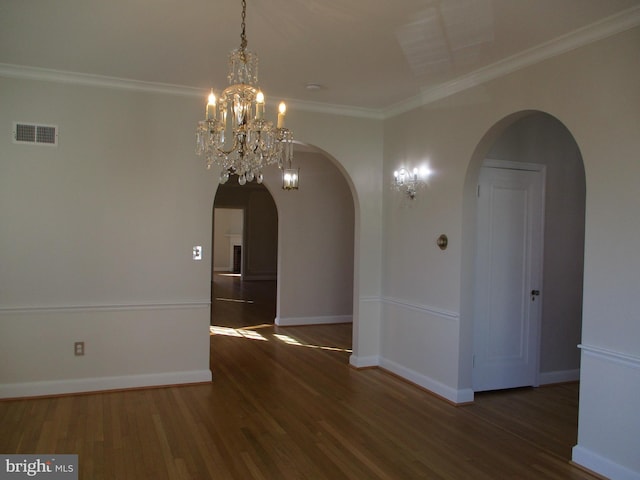 empty room with a chandelier, dark hardwood / wood-style floors, and ornamental molding