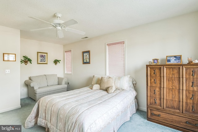 carpeted bedroom with ceiling fan and a textured ceiling