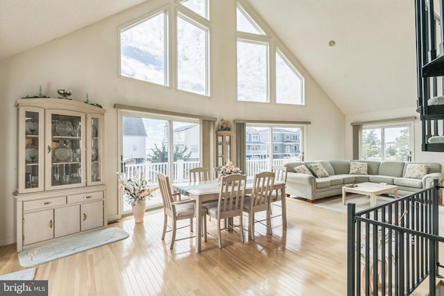 dining space featuring light hardwood / wood-style floors and high vaulted ceiling