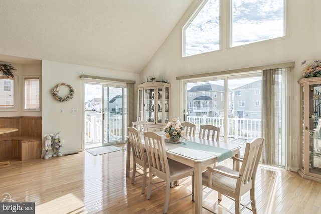 dining area featuring light wood-type flooring and high vaulted ceiling