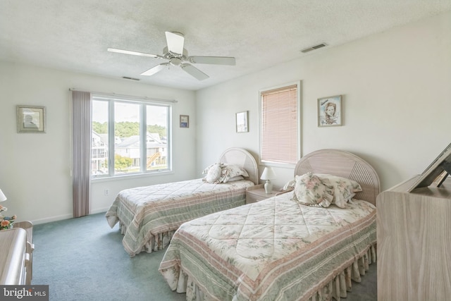 carpeted bedroom with ceiling fan and a textured ceiling