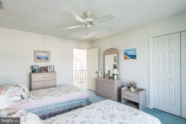 carpeted bedroom featuring a closet, a textured ceiling, and ceiling fan