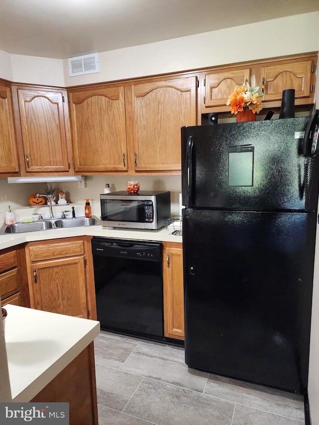 kitchen featuring light tile patterned flooring, black appliances, and sink