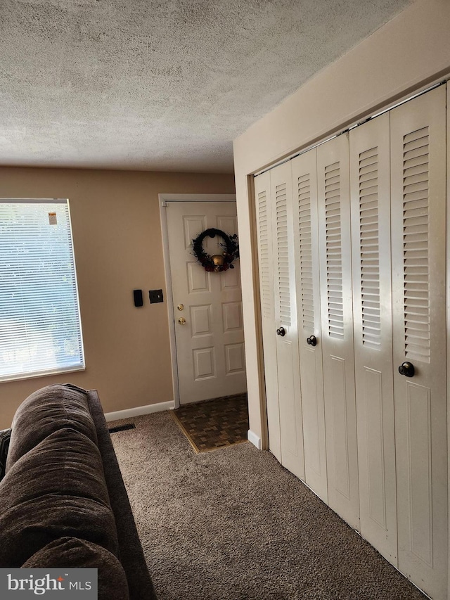 carpeted foyer entrance featuring a textured ceiling