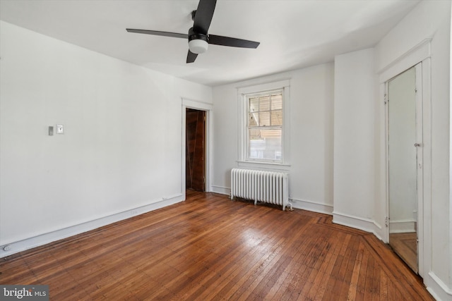 empty room featuring wood-type flooring, radiator heating unit, and ceiling fan