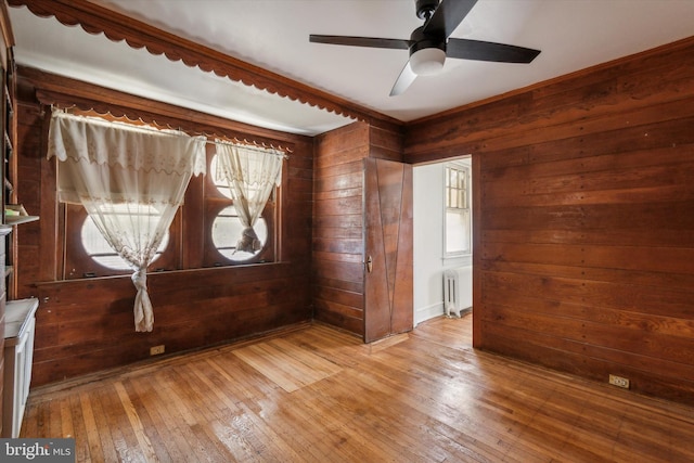 unfurnished room featuring wooden walls, ceiling fan, and wood-type flooring