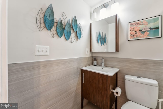 bathroom featuring vanity, toilet, and tile walls