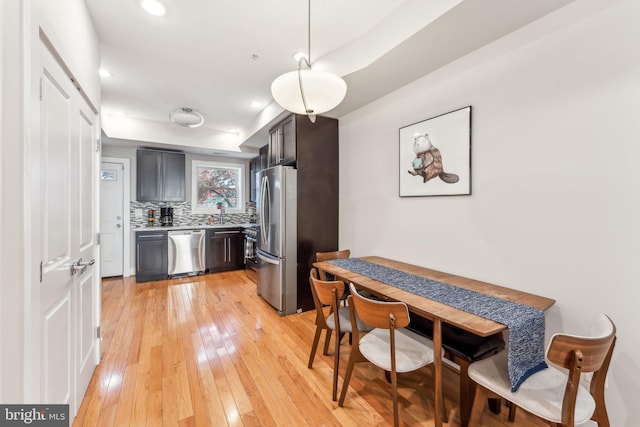 kitchen with appliances with stainless steel finishes, light hardwood / wood-style flooring, and tasteful backsplash