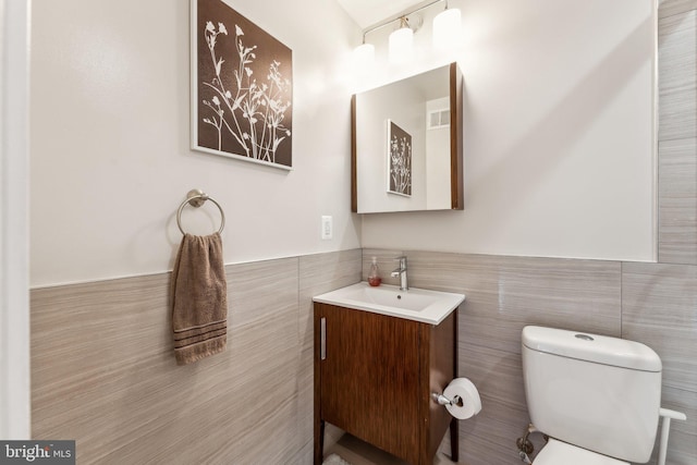 bathroom with vanity, tile walls, and toilet