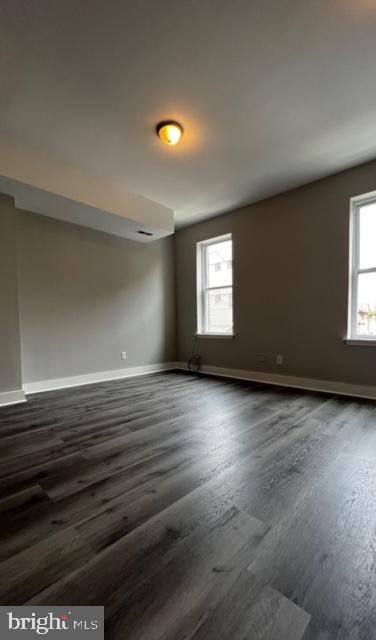 spare room with dark wood-style flooring and baseboards