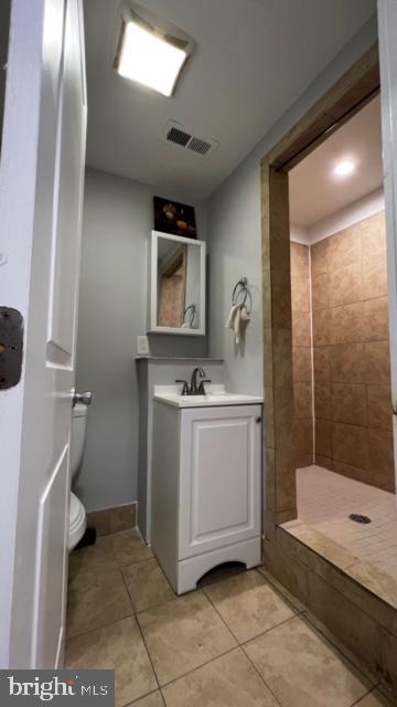 full bath featuring visible vents, toilet, vanity, tile patterned floors, and tiled shower