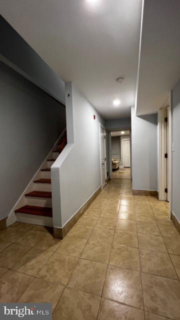 hallway with stairs, baseboards, and light tile patterned flooring