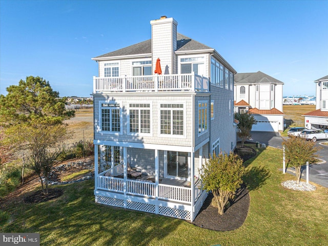 back of property with a sunroom and a lawn