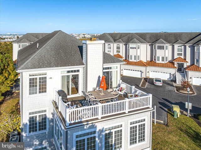 rear view of house featuring a balcony and a garage