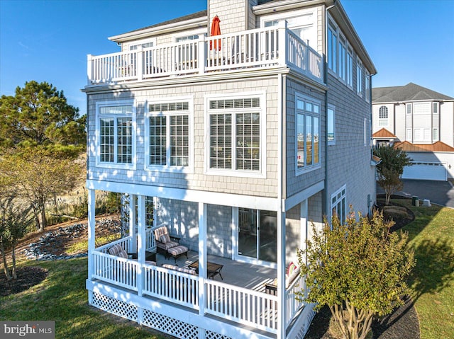 rear view of house with a lawn and a balcony